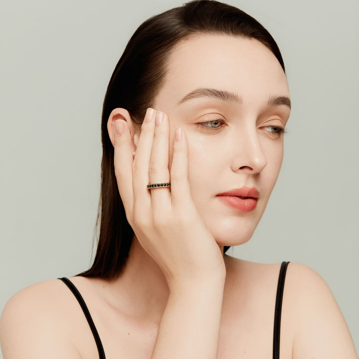 Close-up of intricate goldwork and black diamond setting on model’s hand; elegant and striking.