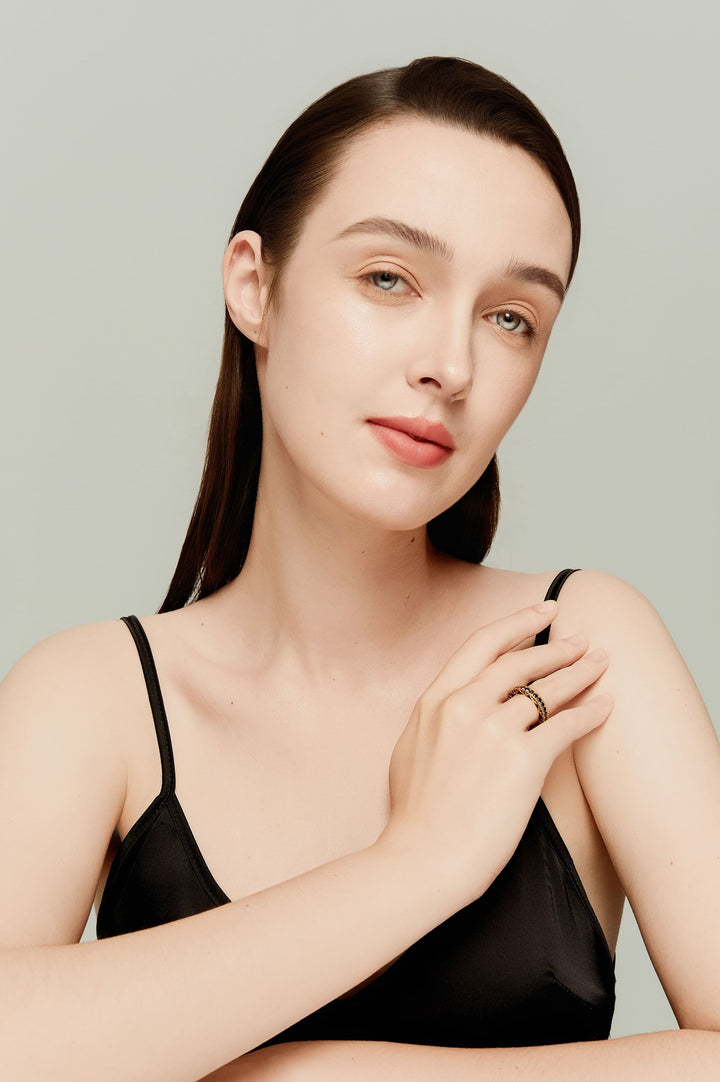 Model wearing bold 14K gold eternity band with black diamonds and ornate side detailing; luxurious and sculptural.