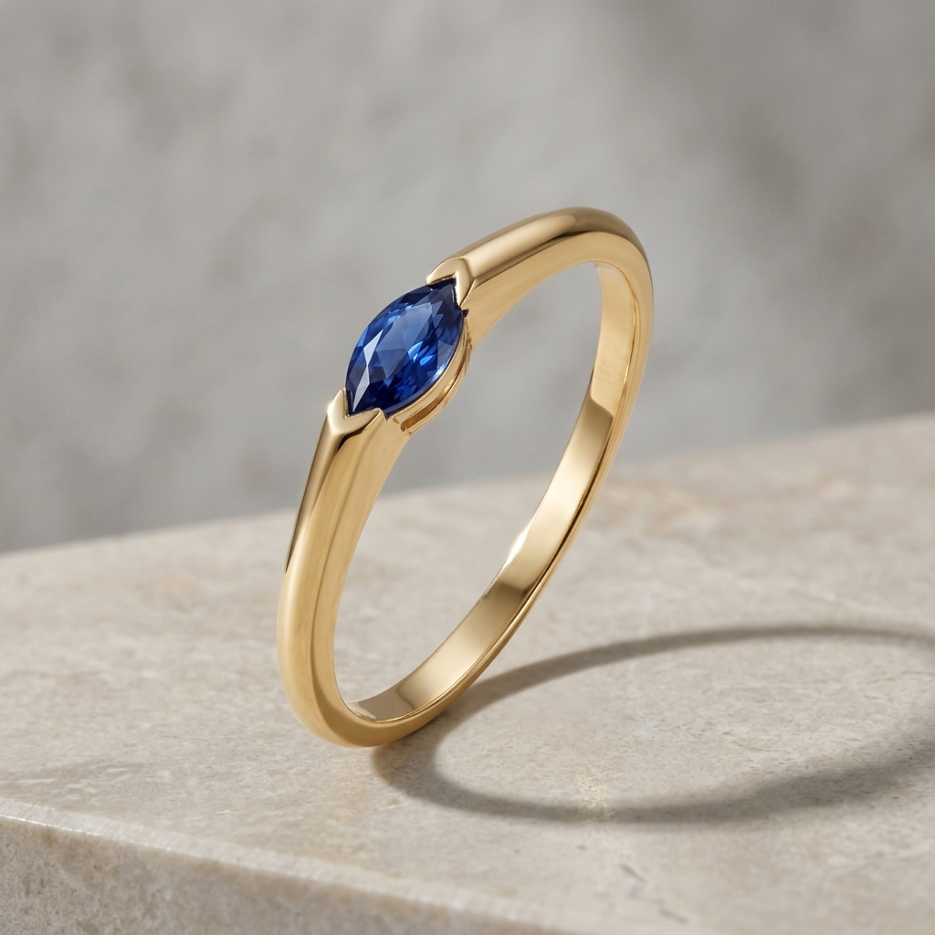 Gold ring with a blue sapphire on a stone surface