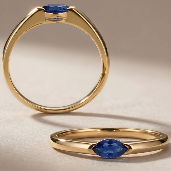 Gold ring with blue gemstone on a beige background