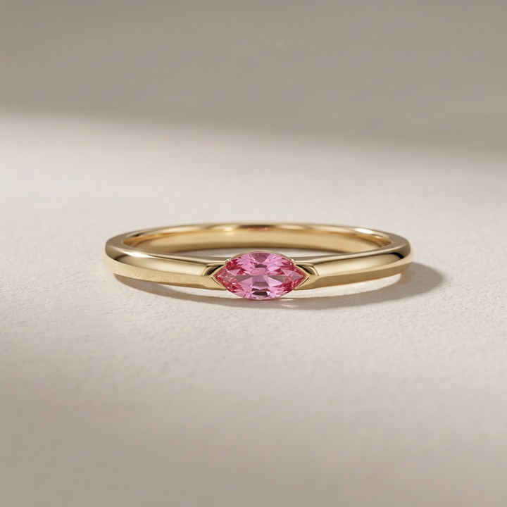 Gold ring with a pink gemstone on a beige background