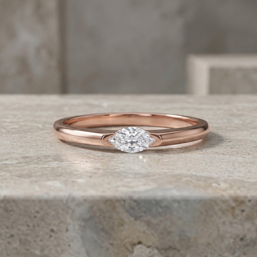 Rose gold ring with a diamond on a stone surface