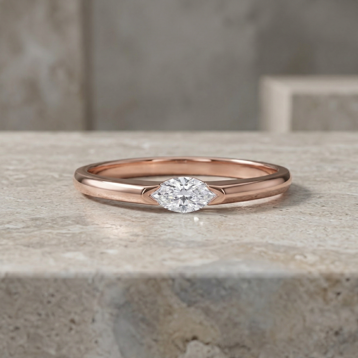 Rose gold ring with a diamond on a stone surface